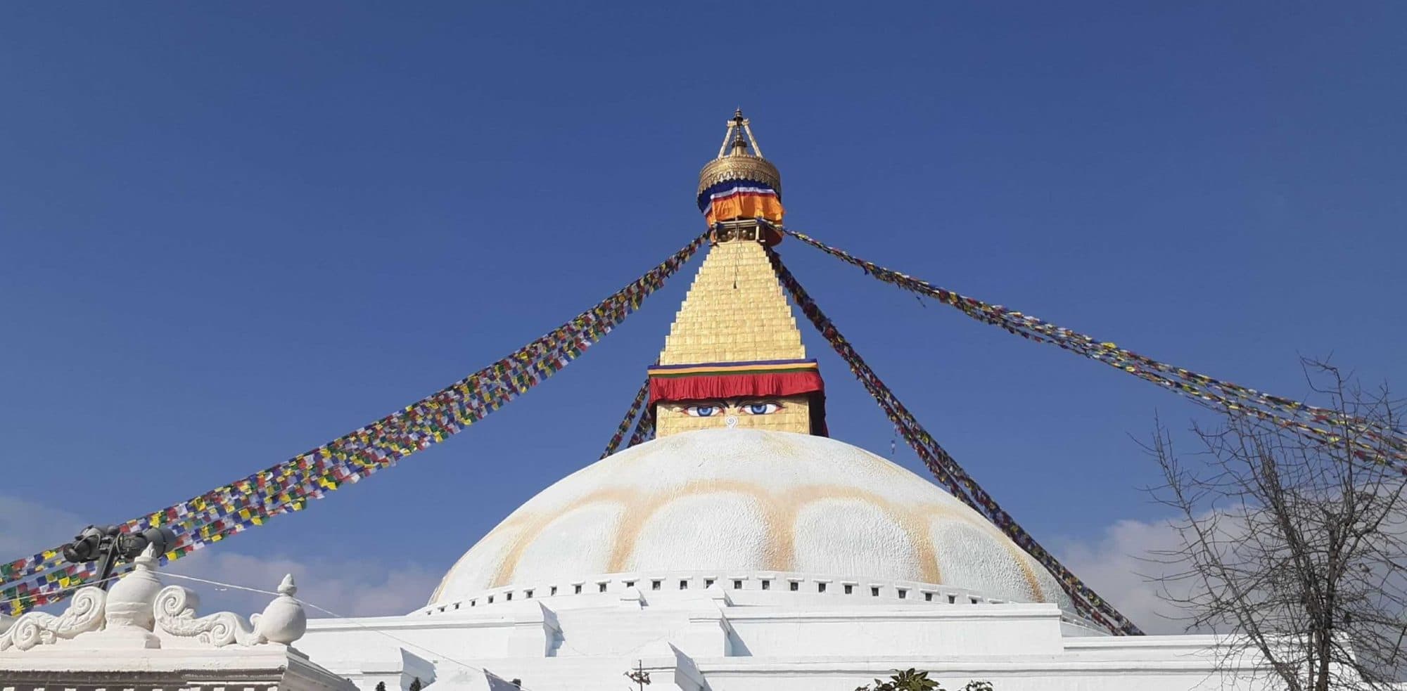 A stupa strung with prayer flags against a clear sky